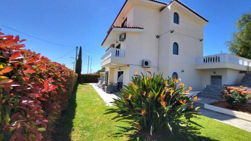 a white house with flowers in front of it at Villa Golden Sun with swimming pool and jacuzzi in Anavissos