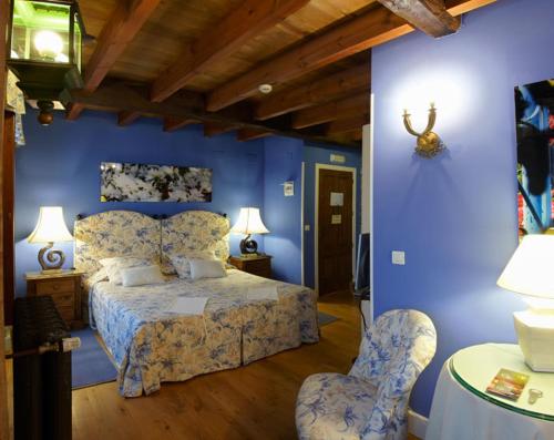 a bedroom with a bed with blue walls and two chairs at Hotel Rural Casa Xusto in La Caridad