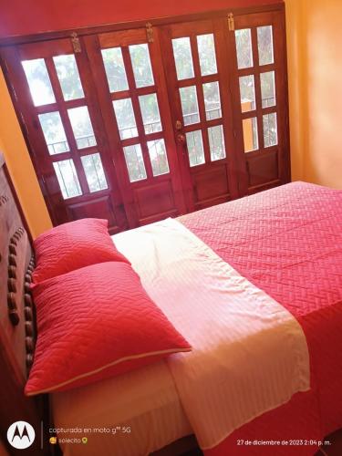 a bed with red pillows in a room with windows at Villa de Asis in Cuaxapa