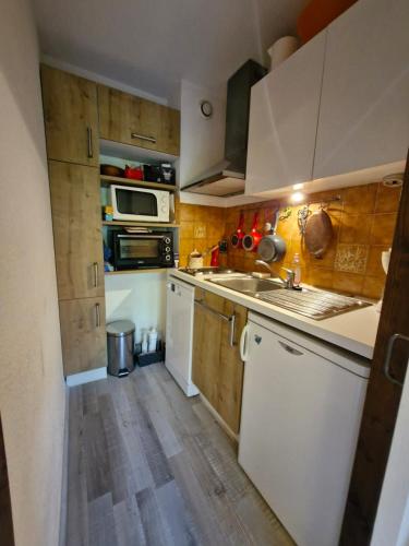 Il comprend une cuisine dotée de parquet et de placards blancs. dans l'établissement Apartment with garden in Demi-Quartier, à Demi-Quartier