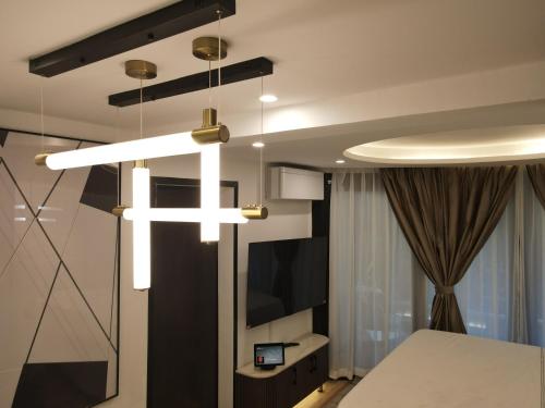 Cette chambre comprend un lit, une télévision et un lustre. dans l'établissement Vita Resort Golf Bastos, à Yaoundé