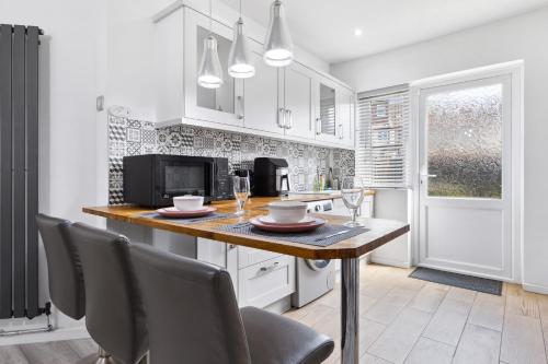 a kitchen with a table with chairs and a microwave at 2-Bed House, Bromley, Free Parking, 30 min to Central London - Sleeps 6 in London