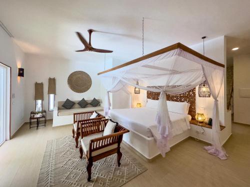 a bedroom with a large bed with a canopy at Alma Boutique Hotel in Jambiani