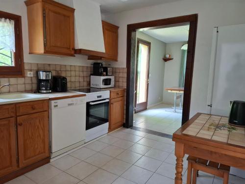 une cuisine avec des appareils électroménagers blancs et des armoires en bois dans l'établissement Gîte Les chalets du Castang, à Valojoulx