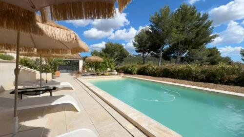 - une piscine dans une villa avec un parasol dans l'établissement Mas Les Murmures, aux Baux-de-Provence