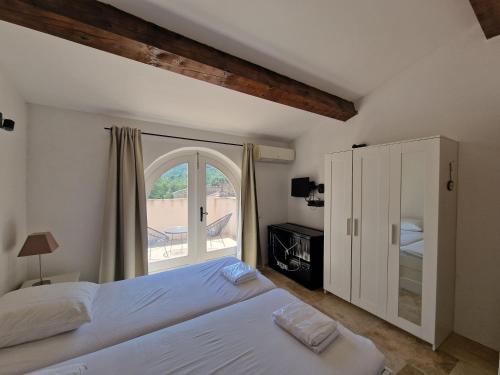 une chambre avec un lit et une grande fenêtre dans l'établissement Hameau Des Claudins, au Plan-de-la-Tour