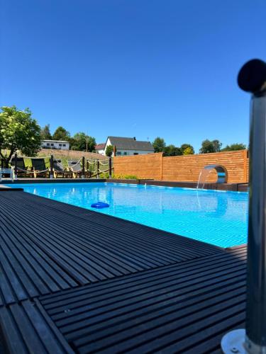 a large swimming pool with blue water on a deck at harmony holiday, Pension in Kerschenbach