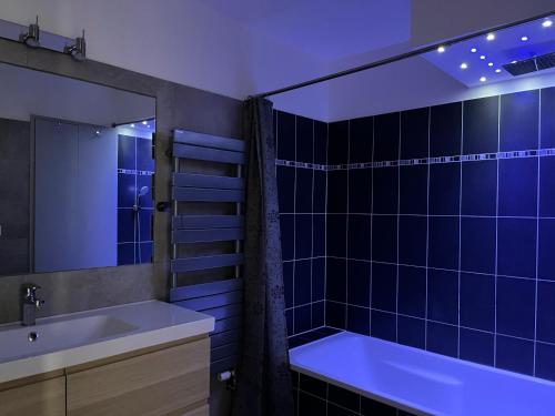 La salle de bains est pourvue de carrelage bleu, d'une baignoire et d'un lavabo. dans l'établissement 3 pièces central au pied de la promenade du paillon, à Nice