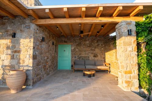 a stone walled patio with a wooden pergola at Villa Zina Sunset View St Lazaros 7 plus 1 Bedroom in Psarou
