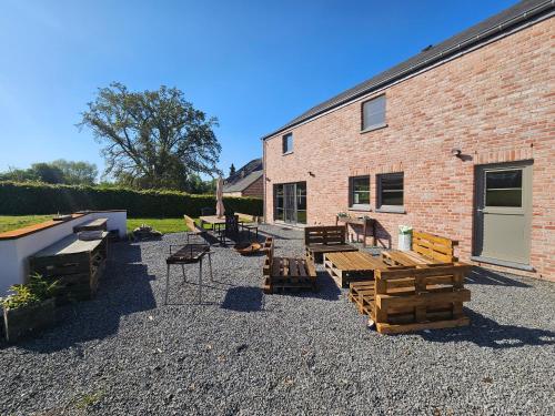 a patio with wooden tables and chairs next to a brick building at La Villa Fer D'art in Houyet