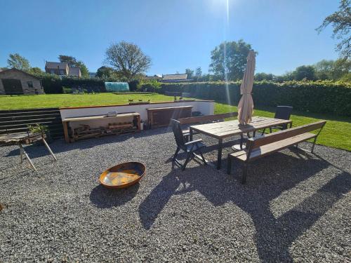 a patio with a table and an umbrella and a bench at La Villa Fer D'art in Houyet