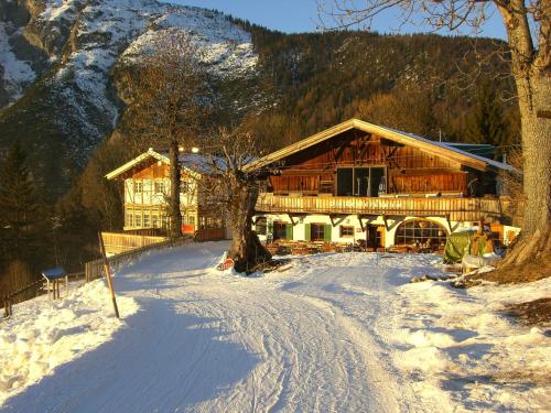 a large wooden house in the snow with a tree at Ropferhof in Telfs-Buchen