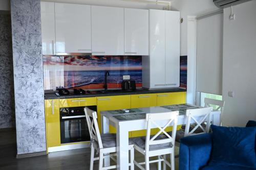 a kitchen with yellow cabinets and a table and chairs at Evo Moonlight by the sea in Mamaia