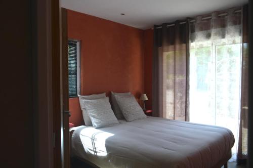 - une chambre avec un lit aux murs orange et une fenêtre dans l'établissement Au Coeur du Bien-Etre, gîte avec piscine chauffée et couverte, SPA, sauna, massages, à Monteaux