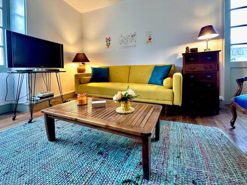 a living room with a yellow couch and a coffee table at Vézelay, Maison de Marita in Vézelay