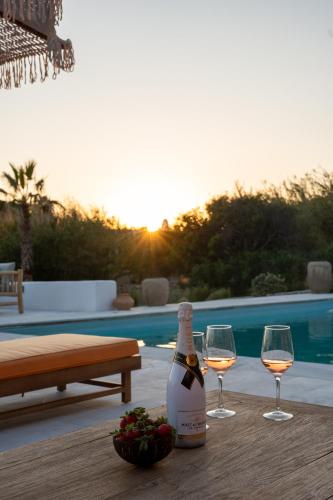 a bottle of wine and two glasses on a table at Villa Zina Sunset View St Lazaros 7 plus 1 Bedroom in Psarou