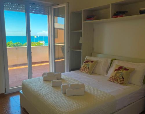 een slaapkamer met een wit bed en uitzicht op de oceaan bij MIRA IL MARE Seaview Apartment - Sunset Lovers' Spot - 50m from the Beach LAVINIO MARE in Anzio
