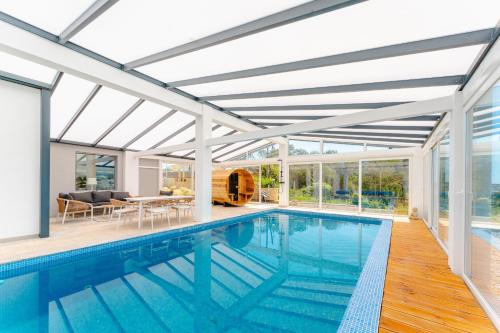 an indoor swimming pool with a glass roof and a house at Villa Moinhos da Costa in Foz do Arelho
