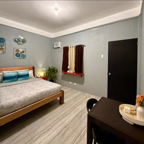 a bedroom with a bed and a desk and a table at Shanti's Inn in General Luna