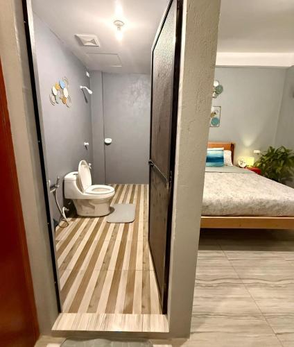 a bathroom with a toilet and a bed in a room at Shanti's Inn in General Luna