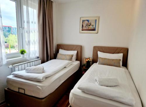 two beds in a room with a window at Apartment Pacifik Lux & Private Garage in Sarajevo