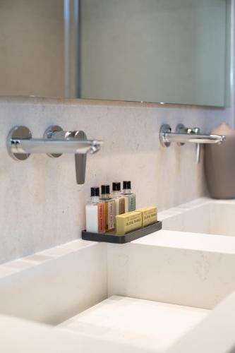a bathroom sink with two faucets and books on a shelf at Paradise View Hotel in Paradise Beach