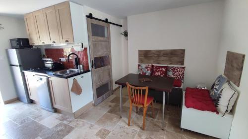 a small kitchen with a table and a refrigerator at Gîte Lydmalida cocon Ardéchois in Les Ollières-sur-Eyrieux