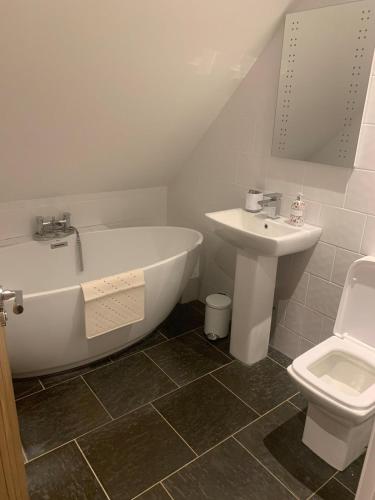 a bathroom with a tub and a sink and a toilet at Bramble Cottage in Mickleton