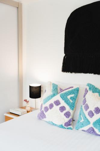 a white bed with blue and purple pillows on it at The Gallery in Mexico City