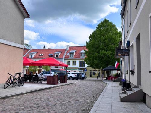 a cobblestone street with tables and chairs and buildings at Apartament A - Rynek 4, Pasym in Pasym