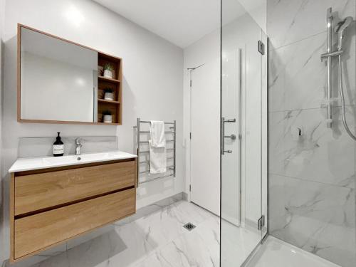 a white bathroom with a sink and a shower at Spacious Allen Street 1BR Stay in Christchurch