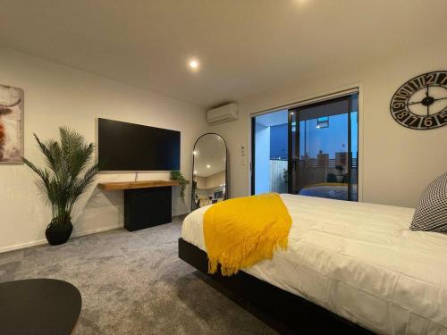 a bedroom with a large bed and a flat screen tv at Stylish and Lush CBD Studio in Christchurch