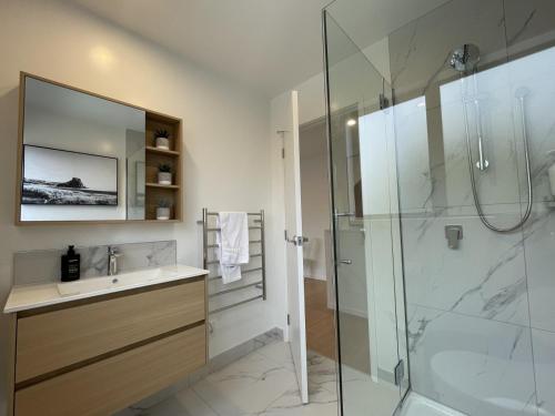 a bathroom with a sink and a glass shower at Relaxing CBD Getaway in Christchurch