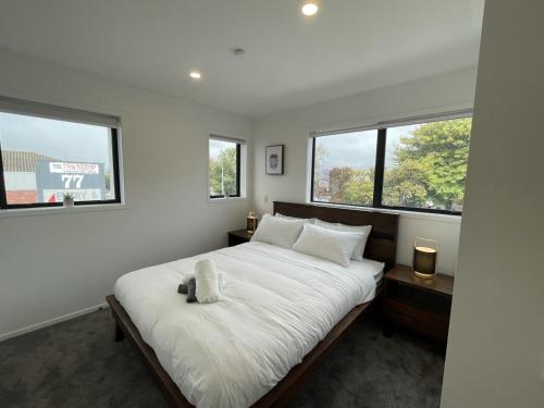 a bedroom with a large white bed with two windows at Relaxing CBD Getaway in Christchurch