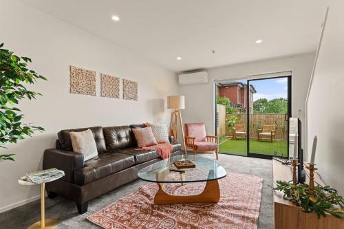 a living room with a couch and a glass table at Alluring and Well-decorated Home in Auckland