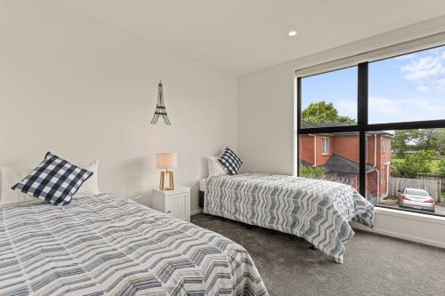a bedroom with two beds and a large window at Alluring and Well-decorated Home in Auckland