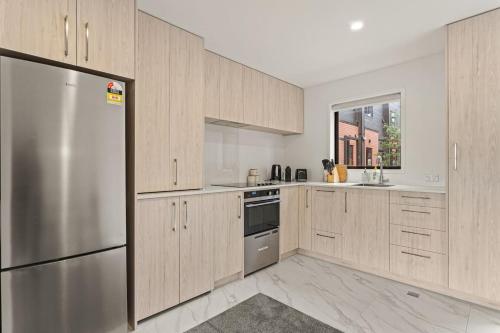 a kitchen with wooden cabinets and a stainless steel refrigerator at Alluring and Well-decorated Home in Auckland