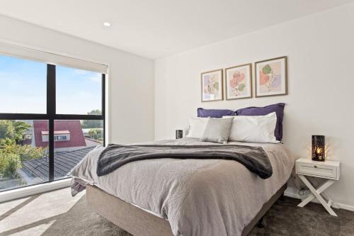 a bedroom with a large bed and a large window at Central Auckland Townhouse in Auckland