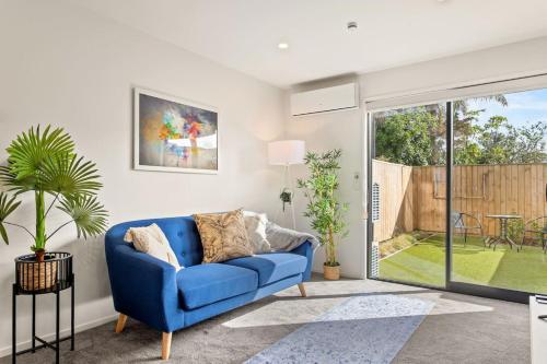 a blue couch in a living room with a sliding glass door at Central Auckland Townhouse in Auckland