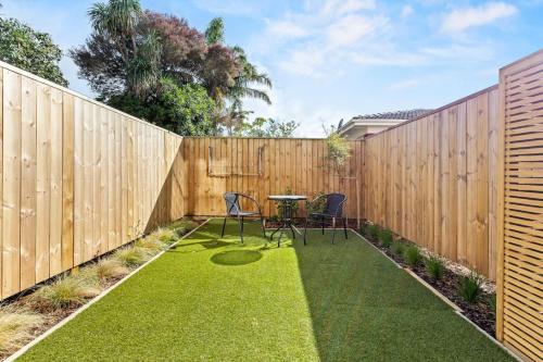 a backyard with a wooden fence with a table and chairs at Central Auckland Townhouse in Auckland