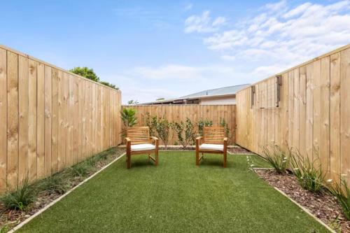 two chairs sitting on a lawn in front of a fence at Comfortable Family Home in Auckland