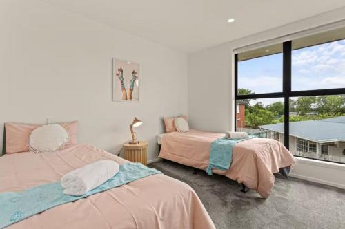 two beds in a room with a window at Comfortable Family Home in Auckland