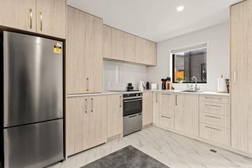 a kitchen with wooden cabinets and a stainless steel refrigerator at Comfortable Family Home in Auckland