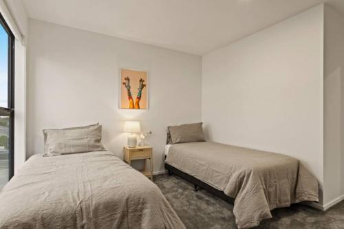 une chambre avec deux lits et une table avec une lampe dans l'établissement Well-styled Vibrant 2 Bed Home, à Auckland