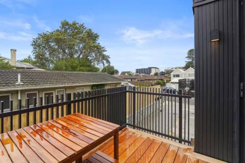 a wooden bench on a deck with a black fence at Stunning Bay of Plenty 2 Bed in Tauranga