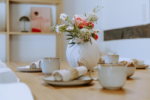 a table with plates and a vase with flowers on it at Tonis Traumhaus in Rietberg
