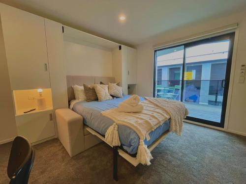 a bedroom with a bed and a large window at Cosy City Centre Studio in Christchurch