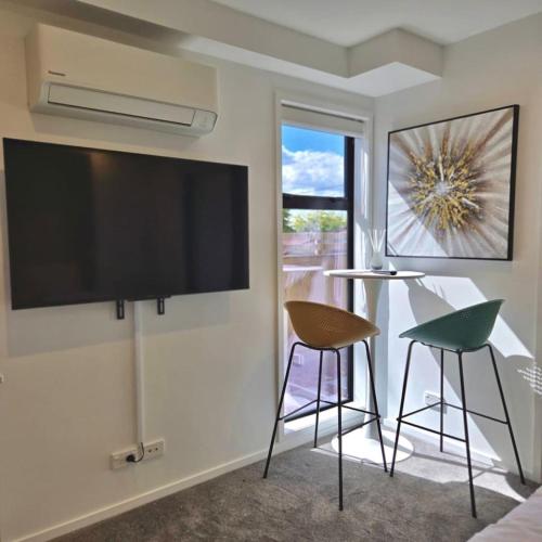 a living room with a large flat screen tv on the wall at Charming Sunnyvale Studio in Auckland