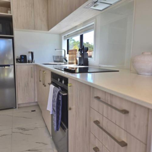 a kitchen with wooden cabinets and a stove top oven at Charming Sunnyvale Studio in Auckland