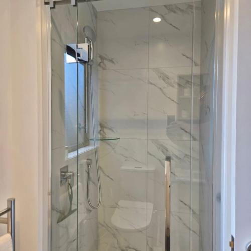 a bathroom with a shower with a glass door at Charming Sunnyvale Studio in Auckland
